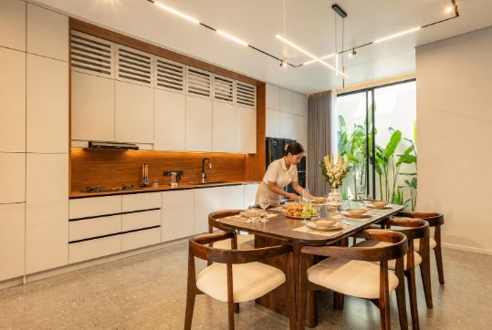 Villa host setting the dining table in a modern Bali villa kitchen