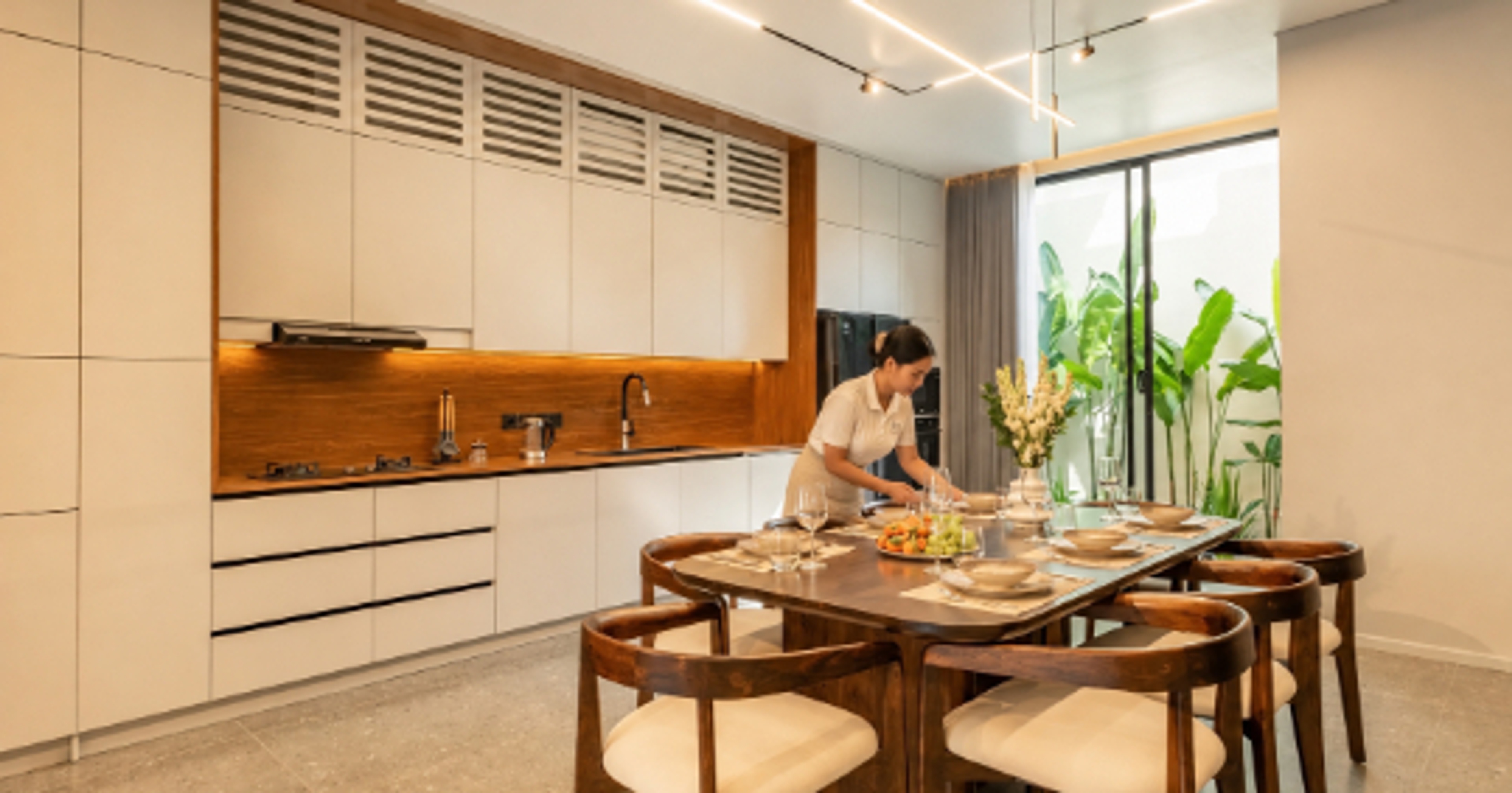 Villa host setting the dining table in a modern Bali villa kitchen