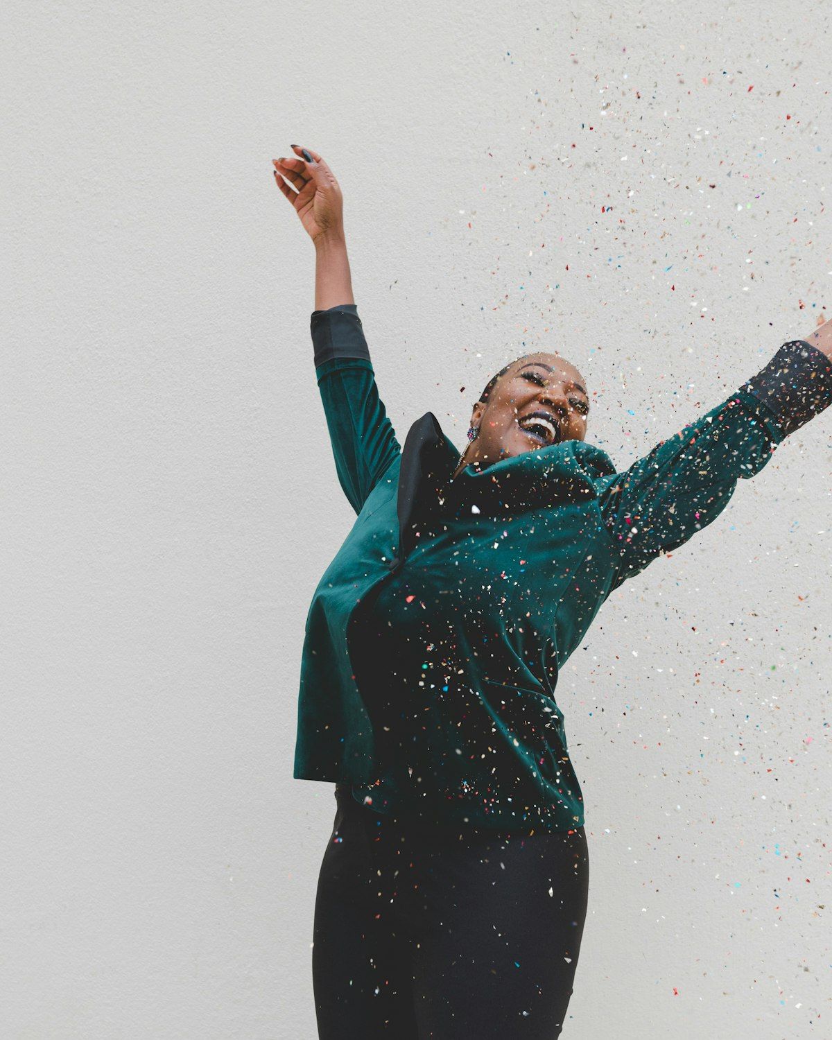 A woman in green with arms raised — confidence, joy and self-awareness