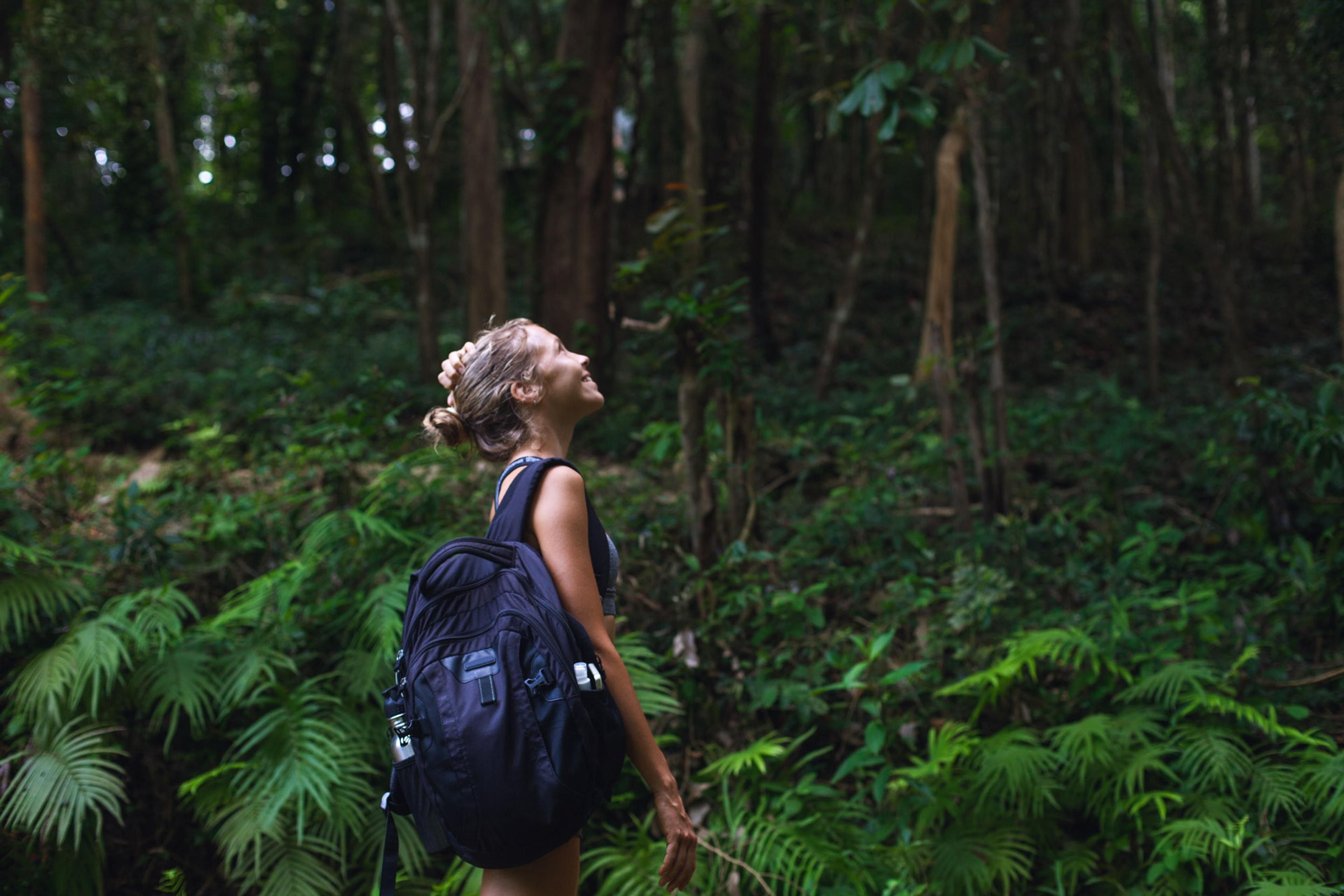 A smiling female hiker looking up in a jungle