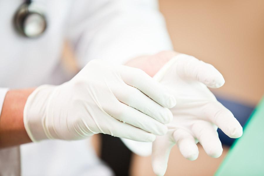 Close up of a person's hand removing white gloves