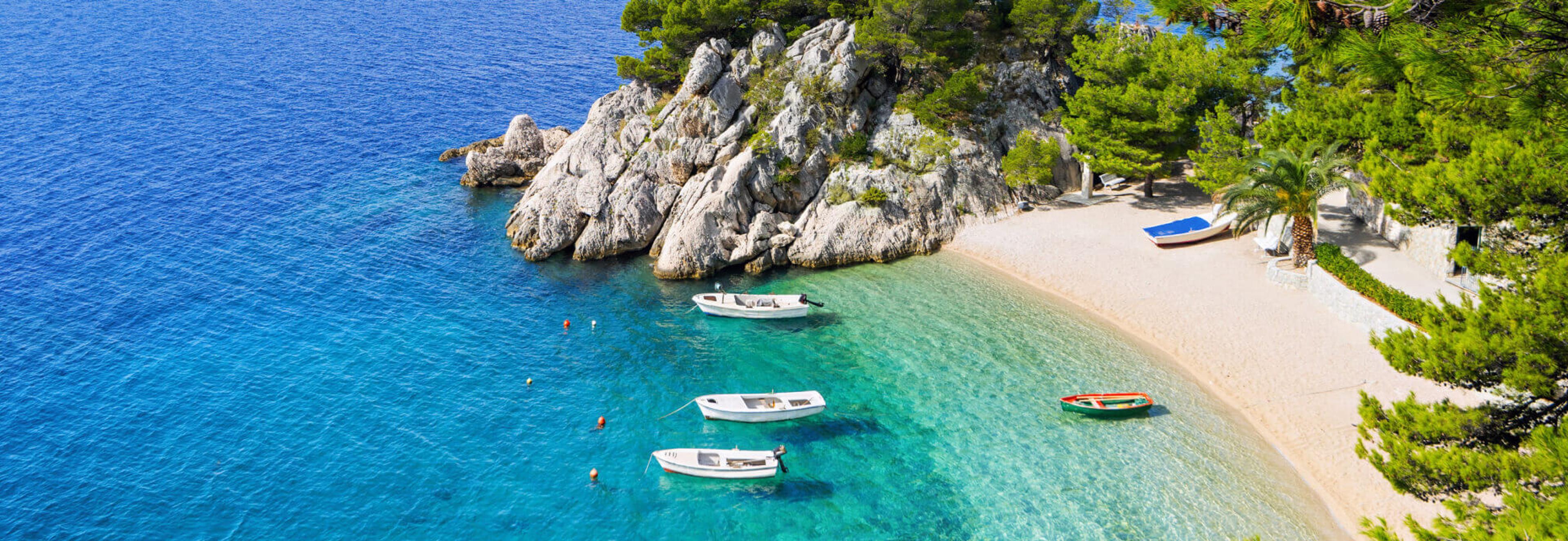 Clear blue lagoon from above with boats moored near the coast 