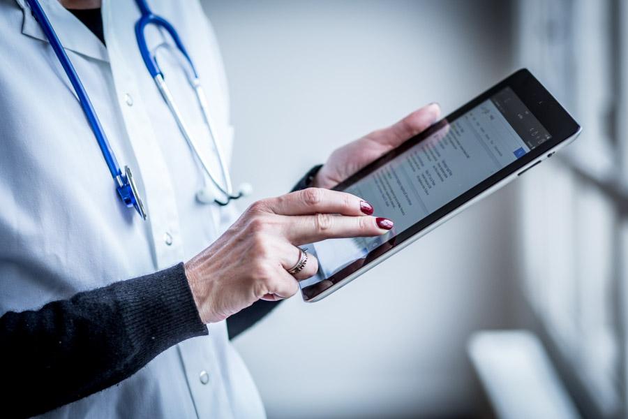 Close up of a healthcare professional's hand holding an iPad and scrolling through