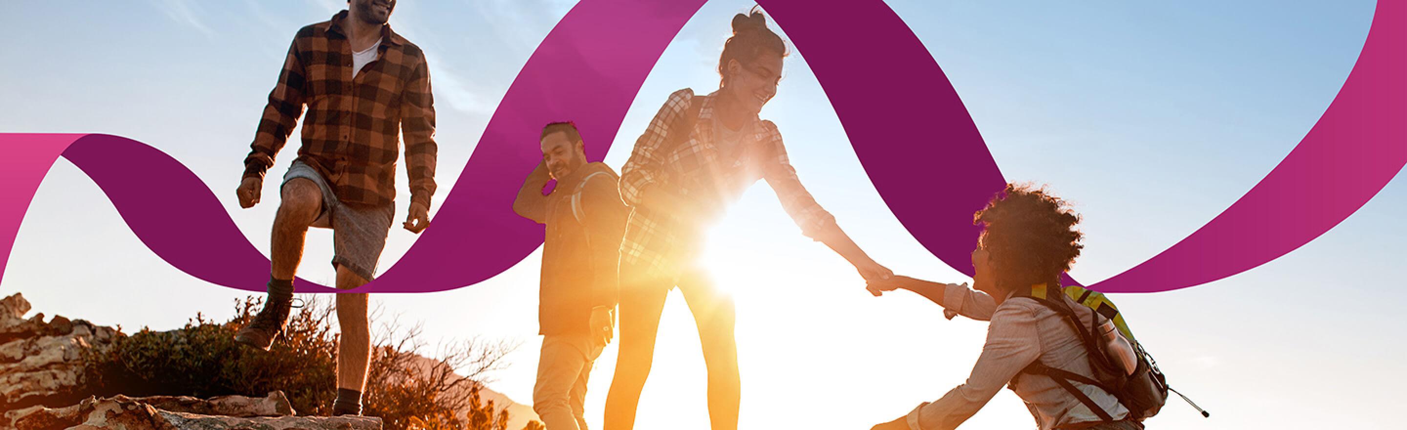 Group of hikers in the sun with one woman being helped to climb up