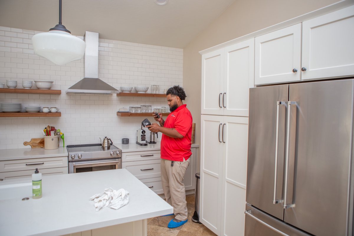 A technician checking a kitchen wall with a moisture meter after a storm