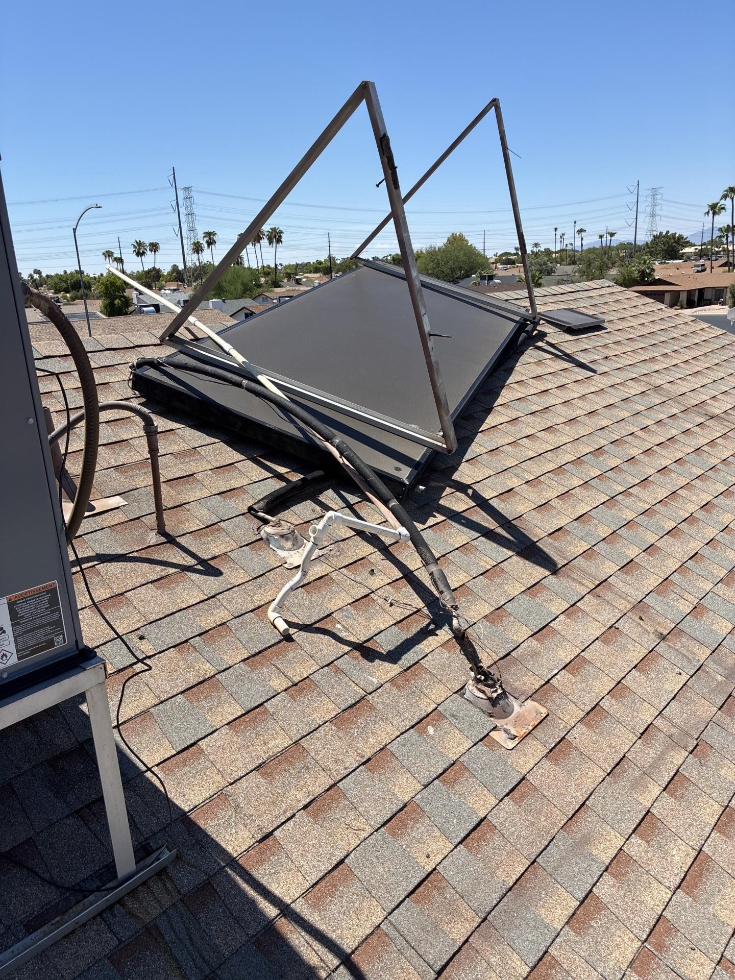 Solar panel torn loose and hanging from a shingle roof after a microburst, with the condensate line pulled away