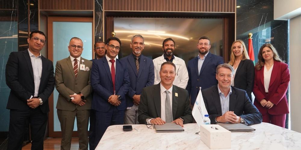 Leadership from Verita Healthcare Group and Fakeeh University Hospital gathered in formal attire during a partnership meeting in a wood- and marble-paneled boardroom.