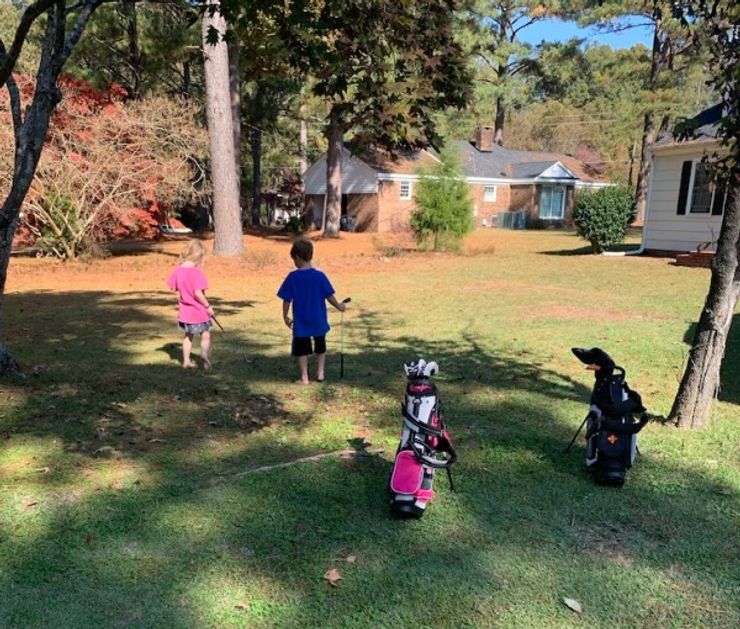Two junior golfers practicing out in their yard at home