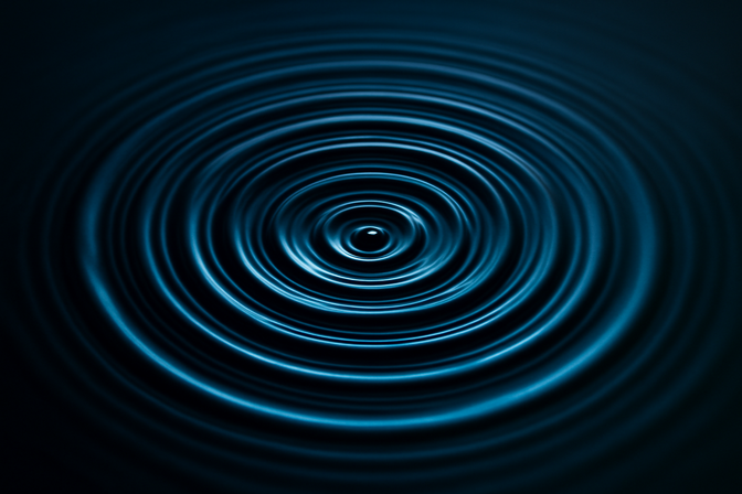 Concentric ripples spreading outward across a still, reflective water surface viewed from above