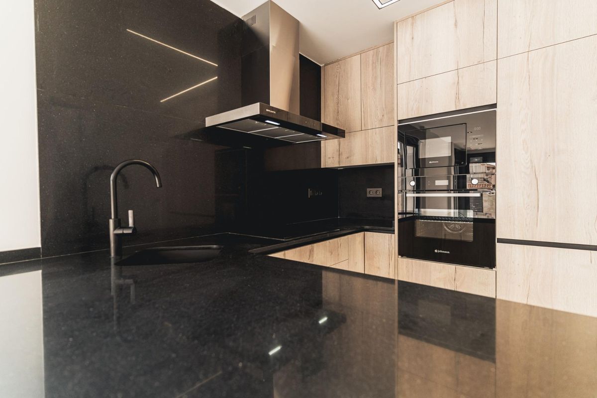 Detailopname van zwarte en houten keuken kenmerken met moderne apparaten in Orihuela Costa, Spanje.