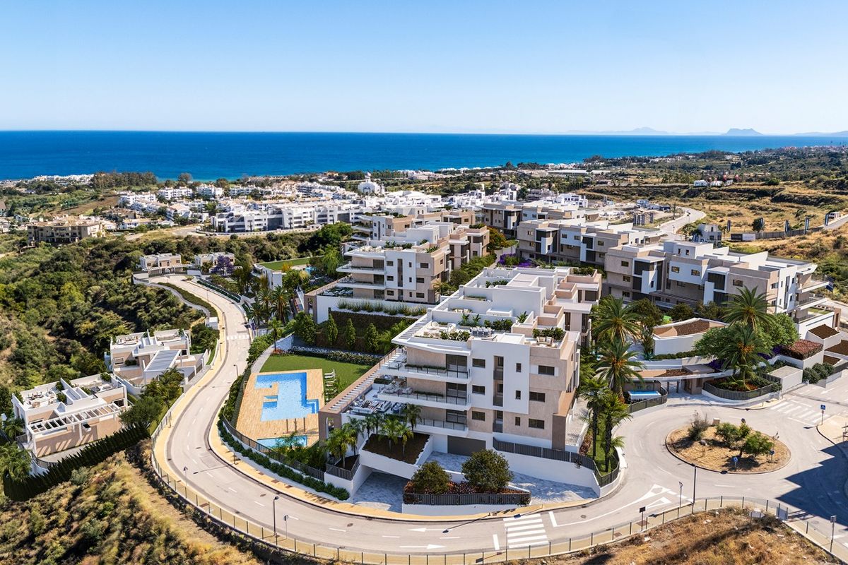 Luchtfoto van een modern duplexcomplex in Estepona, omringd door groen en uitzicht op de oceaan.