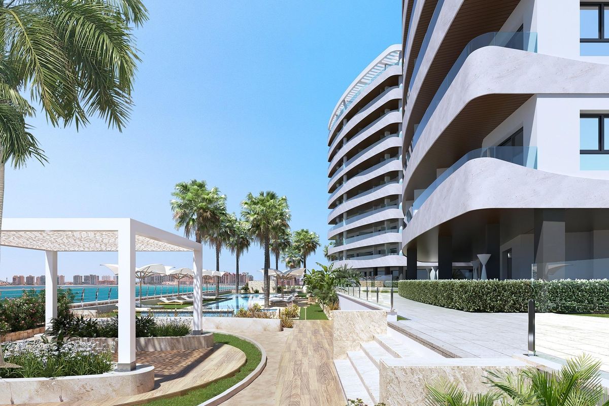 Exterior view of a 1-bed apartment in La Manga del Mar Menor, featuring landscaped areas and palm trees.