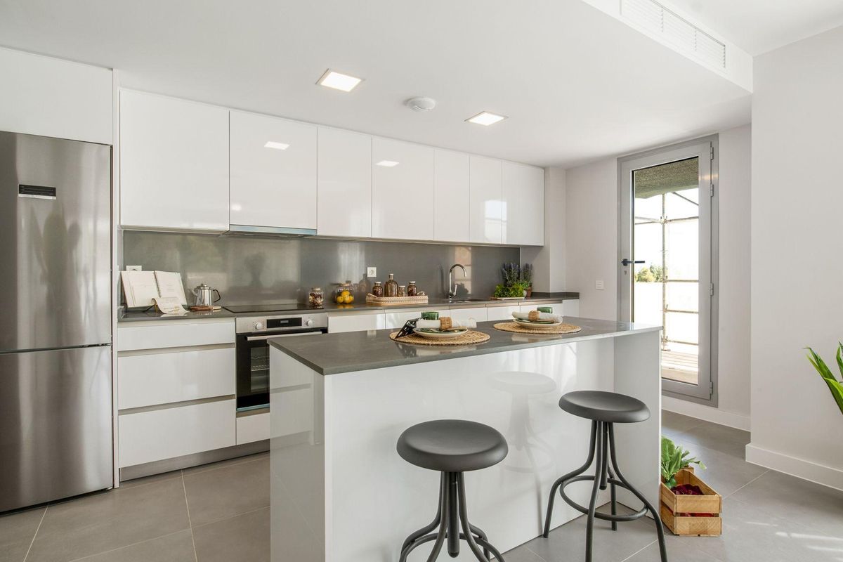 Moderne keuken met strakke witte kasten en een ontbijtbar in een 4-slaapkamer penthouse in Mijas, Costa del Sol.