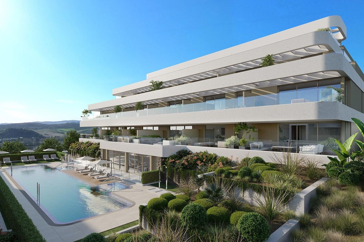 Modern appartement op de begane grond in Estepona met een zwembad omringd door weelderig groen en stijlvolle zitplaatsen.
