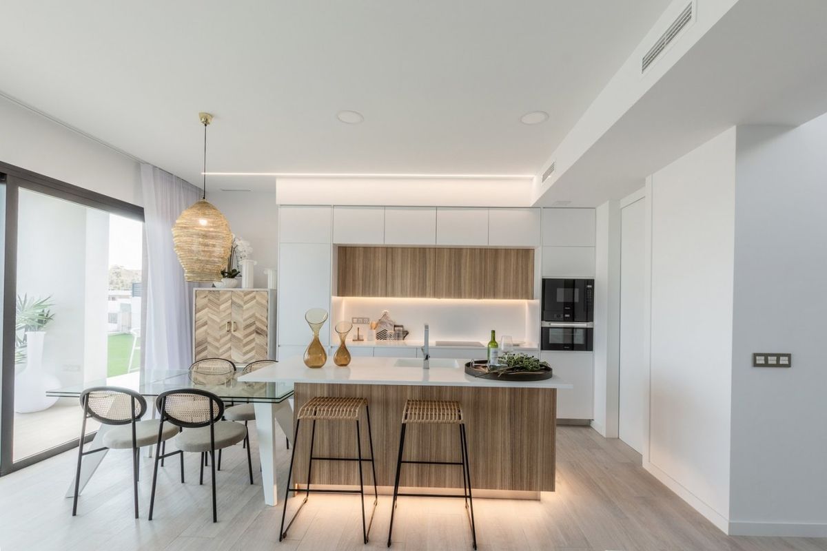 Modern kitchen and dining area in a villa at Costa Blanca North. Features a kitchen island, stools, and sleek design.