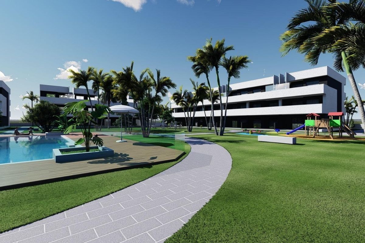 Zwembadgebied van het appartementencomplex in Guardamar del Segura omgeven door palmbomen en groene gazons.