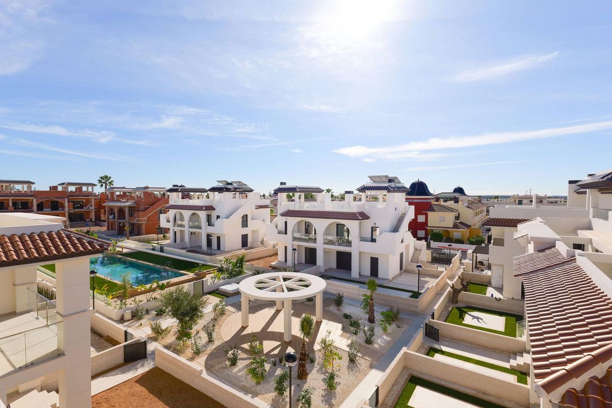 Verre weergave van townhouses en zwembad onder fel zonlicht in Rojales, Costa Blanca Zuid.