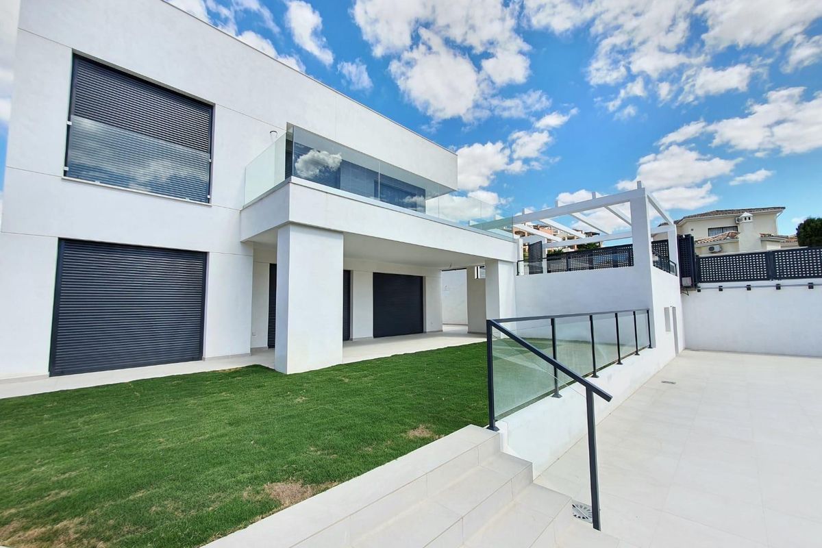 Exterieur van een villa die hedendaags design in Manilva toont, met een ruim terras en groene ruimtes.