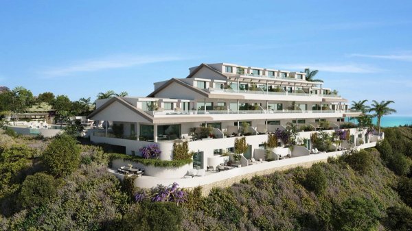 Buitenzijde van een moderne 4-slaapkamerpenthouse in Benalmádena met groene omgeving en oceaan op de achtergrond.