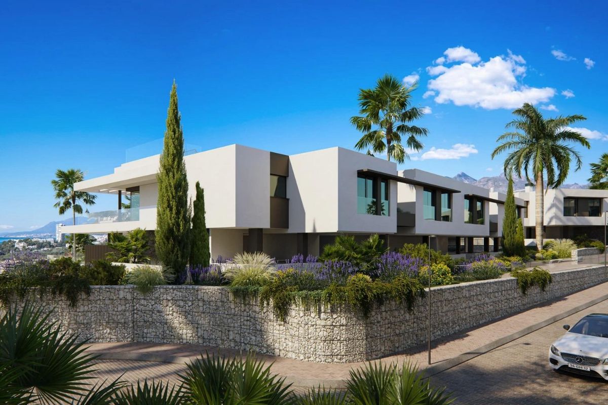 Boeiende uitzicht op een modern appartementencomplex in Marbella met een heldere lucht en weelderig groen eromheen.