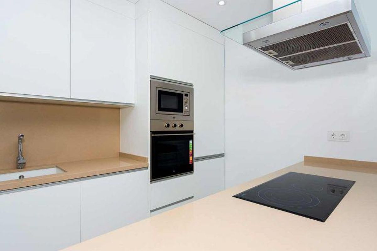 Strakke witte keuken in een bungalow in Daya Nueva, uitgerust met moderne apparaten en veel werkruimte.