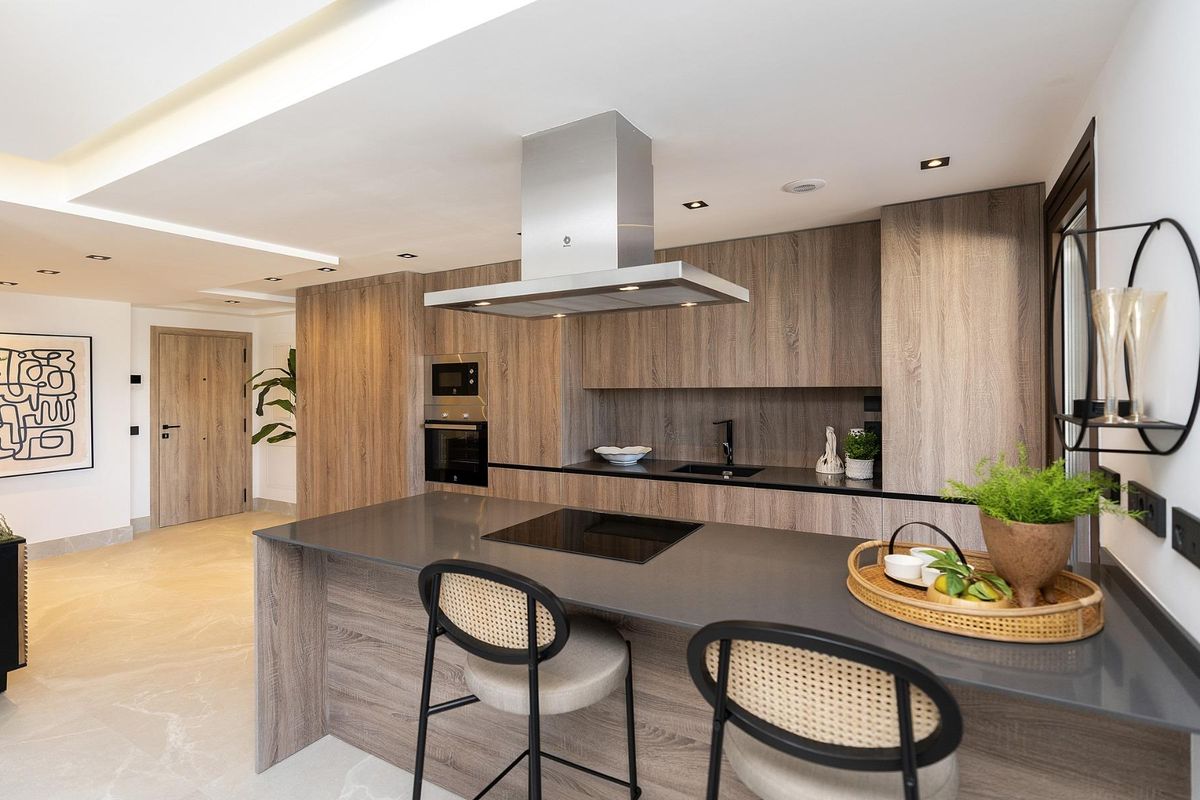 Strakke keuken met moderne apparaten en houten accenten in de penthouse gelegen in Istán, Costa del Sol.