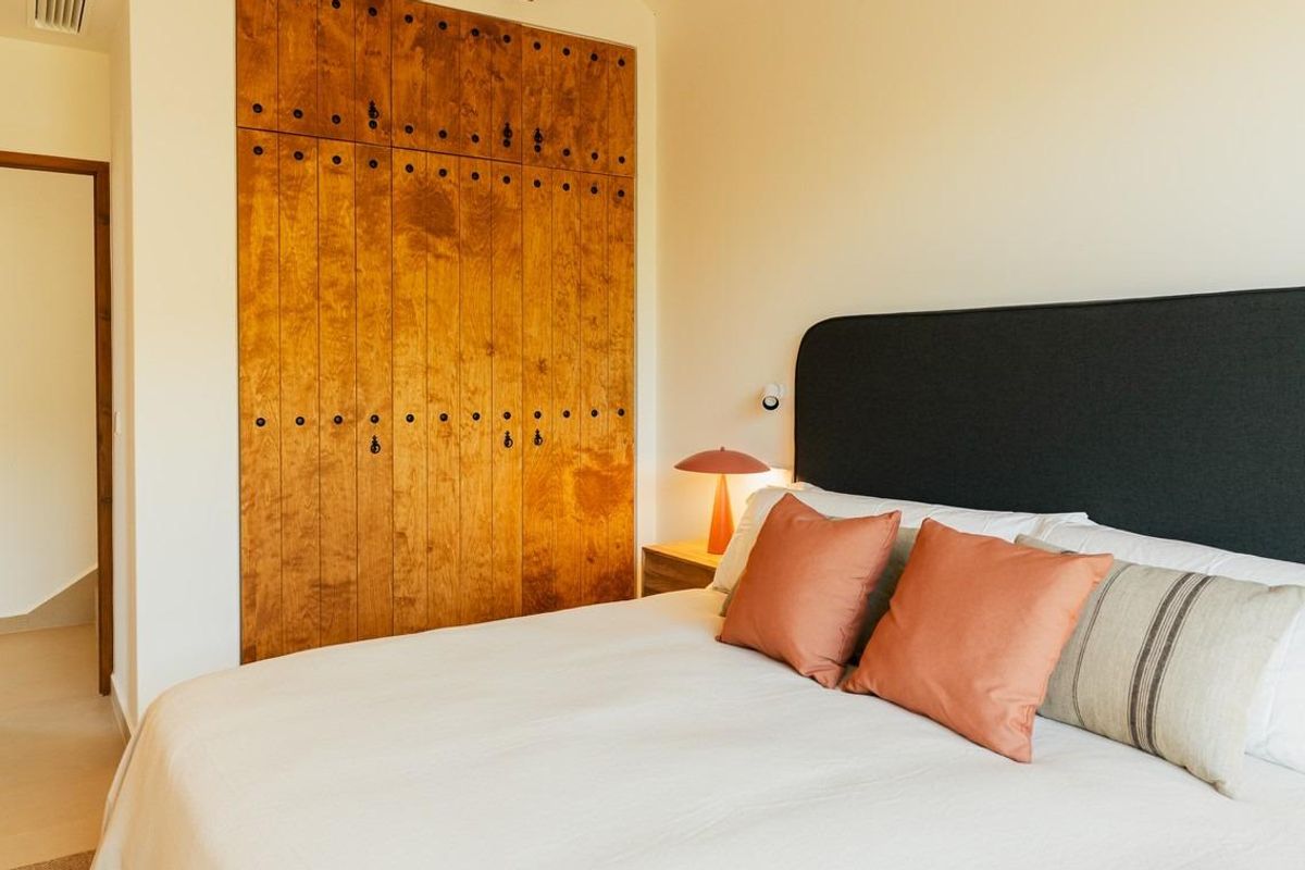 Serene slaapkamer met houten meubels en balken, met toegang tot de tuin in de villa in Jávea.