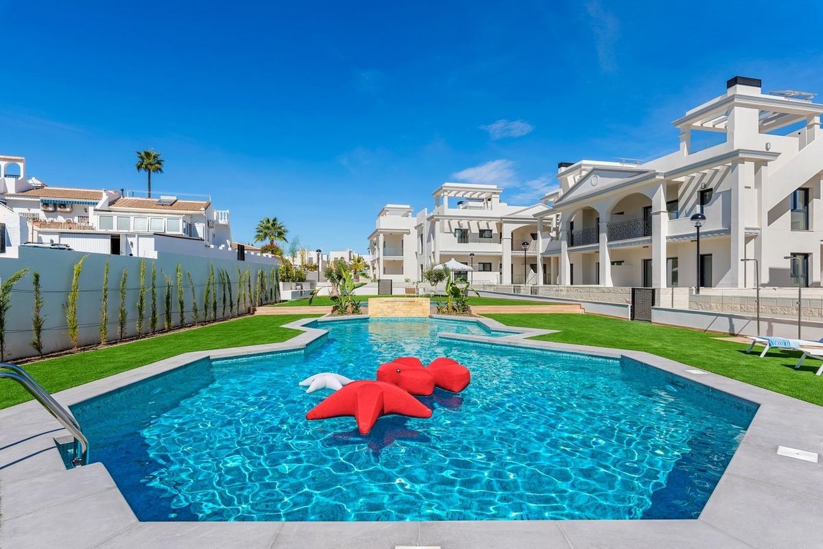 Uitnodigend zwembad met kleurrijke floats, omringd door moderne gebouwen in Rojales, Costa Blanca Zuid, Spanje.