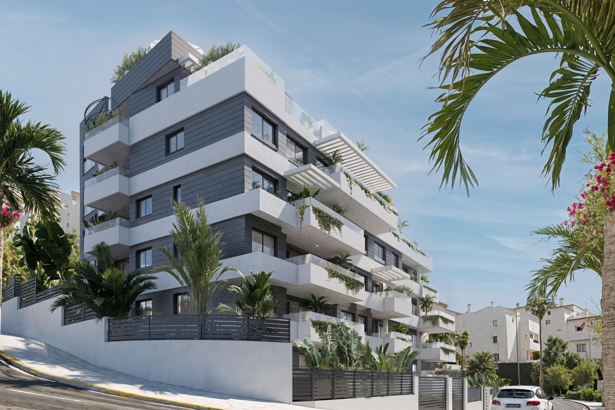 Moderne buitenkant van een 2-slaapkamer appartementgebouw in Estepona, met palmbomen en een zonnige sfeer.
