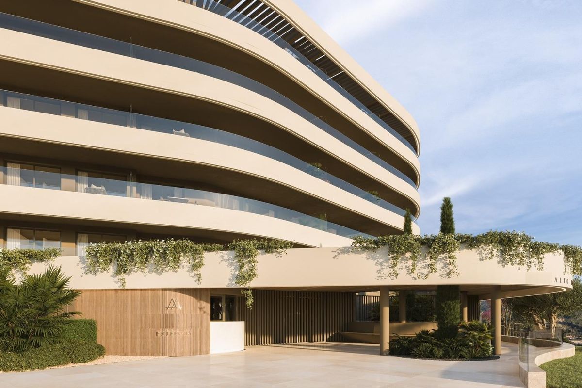 Close-up van de ingang van het stijlvolle appartementencomplex omgeven door groen in Estepona.