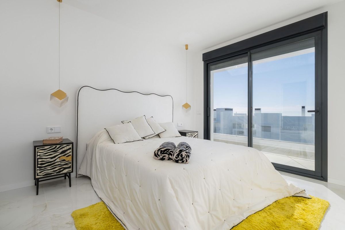 Gezellige slaapkamer in een 3-slaapkamer penthouse in Estepona met een groot raam en prachtig uitzicht.