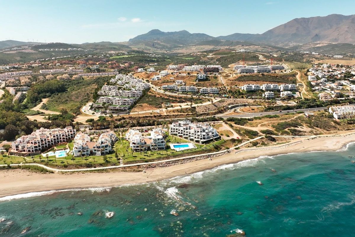 Kustluchtfoto die het strand en appartementen toont te midden van weelderige landschappen nabij Casares.