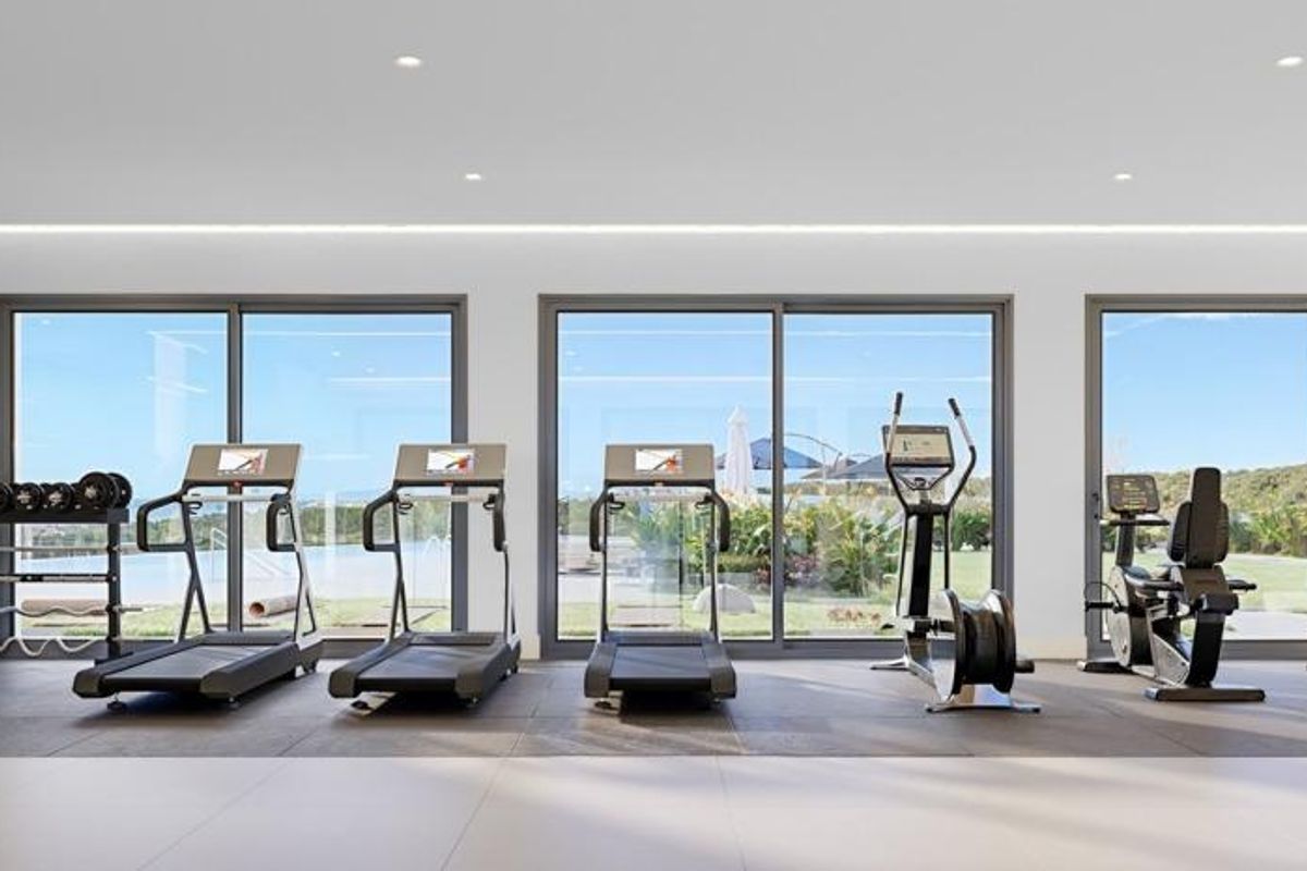 Moderne sportszaal met loopbanden en apparatuur, met grote ramen en een helder uitzicht op Casares.