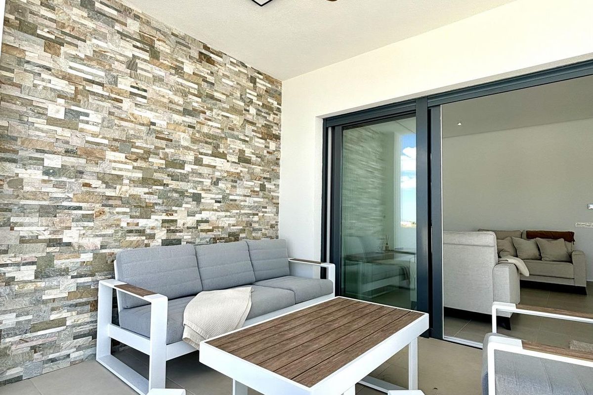 Stijlvol terras met steenwand, zitgedeelte en plafondventilator in een villa in Benijofar.