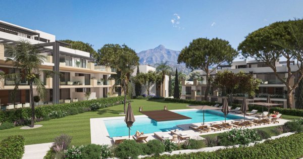 Buitenzicht op een modern appartementencomplex met een zwembad en aangelegde tuin in Marbella, Costa del Sol.
