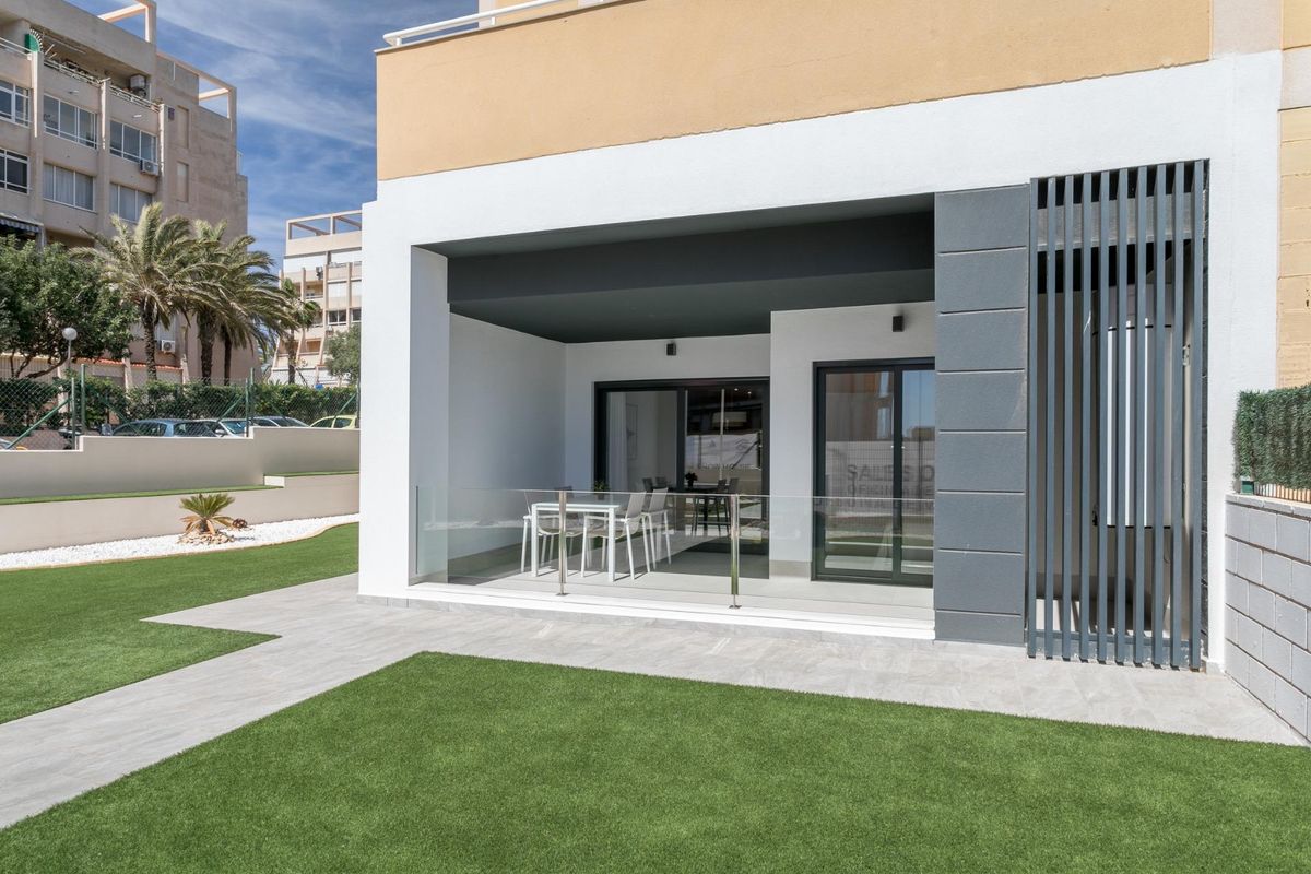 Uitzicht op het terras en tuinsegment van een begane grond appartement in Torrevieja, zonnig en uitnodigend.