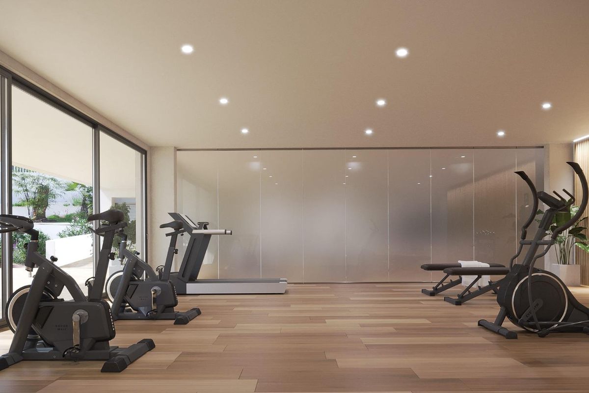 Moderne gym met fitnessmachines en grote ramen in een wooncomplex in Estepona.