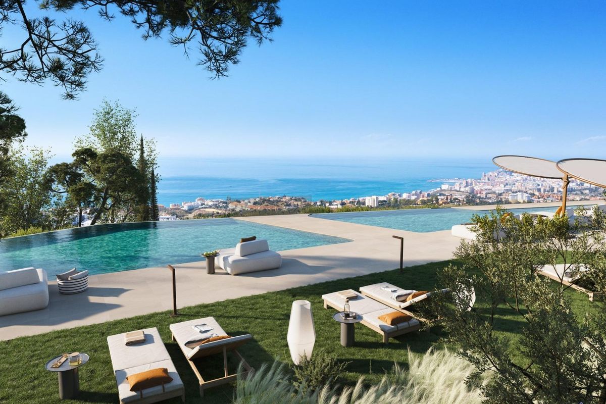 Prachtig panoramisch uitzicht op Fuengirola vanaf een zwembad op de heuvel, omringd door groen en luxe ligstoelen.