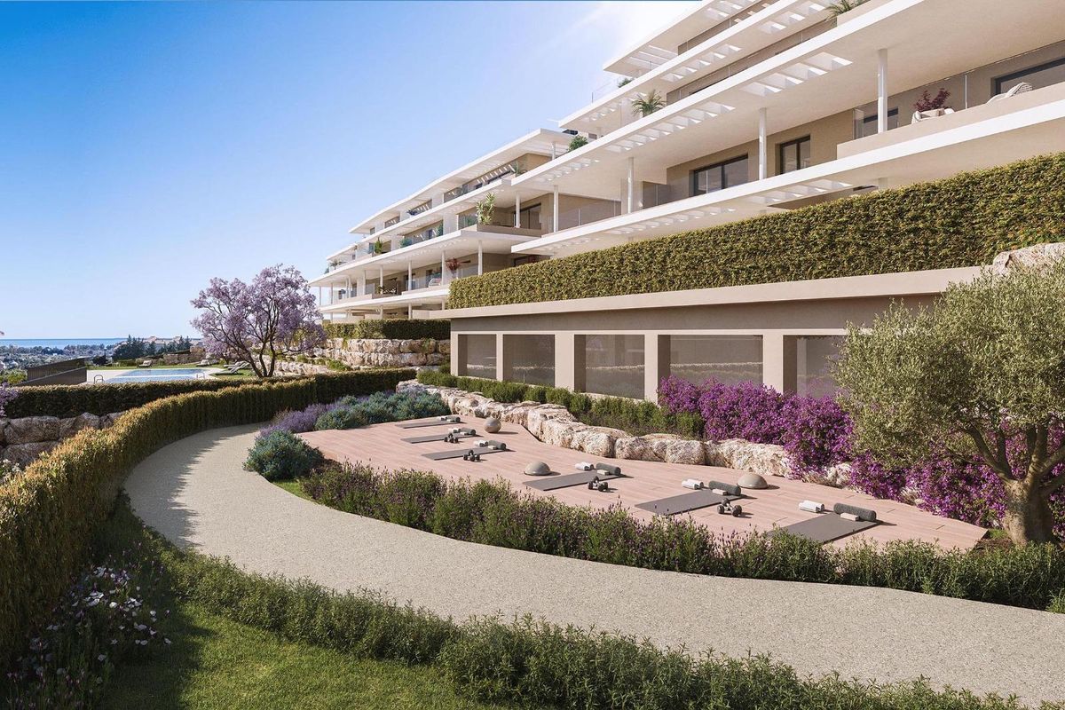Buitenzicht op het moderne penthouse omringd door tuinen in het zonnige landschap van Estepona.