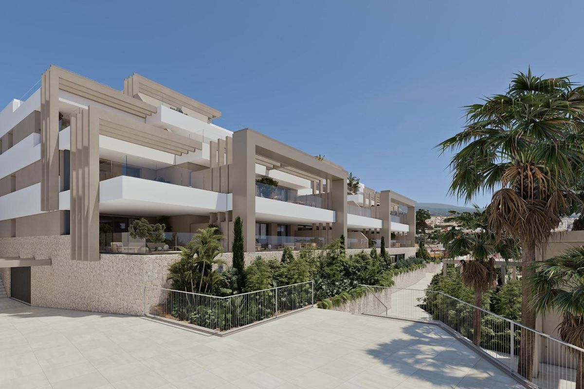 Buitenzicht op het appartementencomplex in Estepona, met moderne architectuur en weelderig groen landschap.