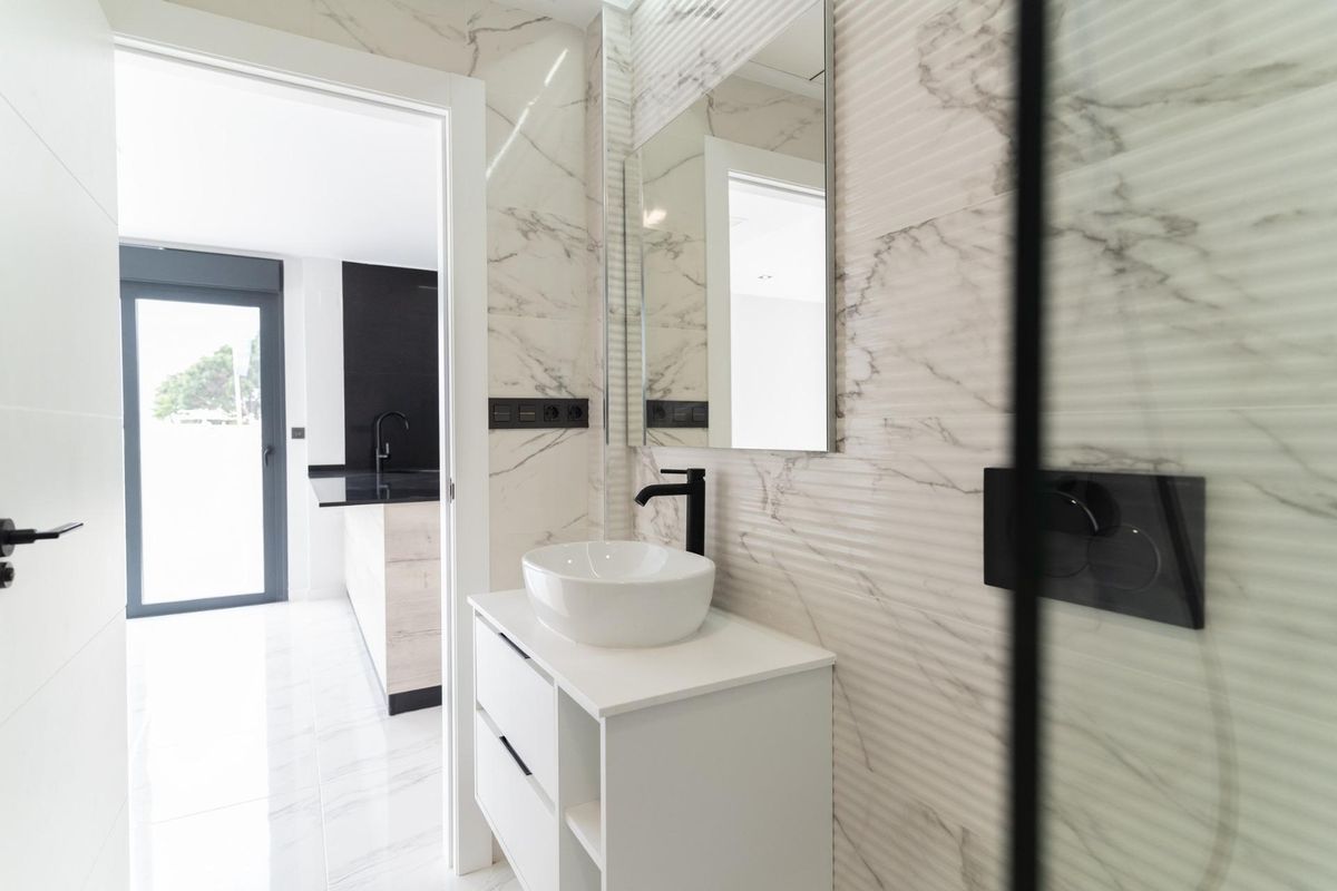 Minimalistisch badkamerontwerp met een stijlvolle wastafel en uitzicht op de keuken in Orihuela Costa, Spanje.