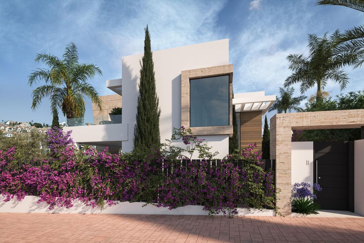 De moderne gevel van een villa in Estepona, omringd door kleurrijke bloemen en groen.