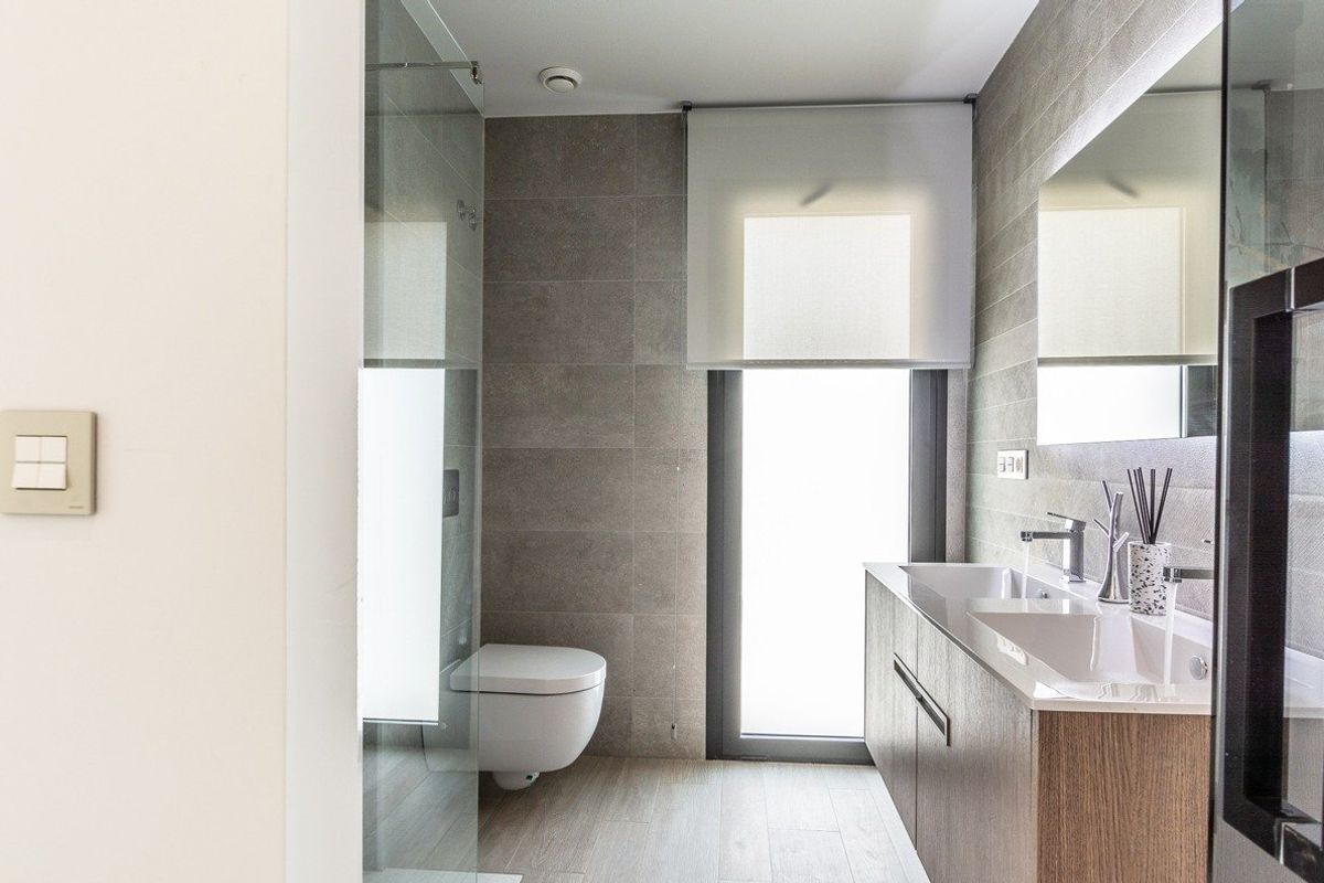 Contemporary bathroom in a Costa Blanca villa, featuring modern fittings, grey tiling, glass shower cubicle and a large mirror.