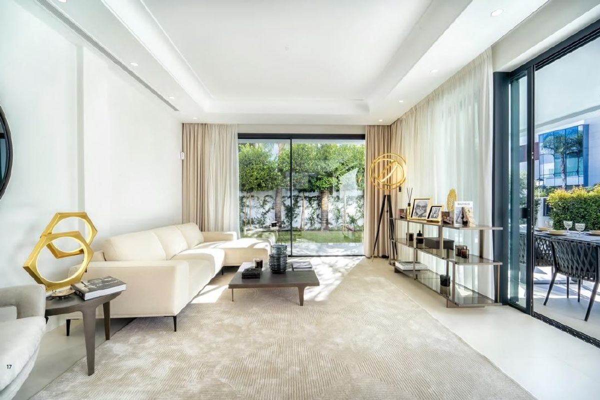 Stijlvolle woonkamer met moderne inrichting en grote ramen met uitzicht op de tuin in villa in Marbella.