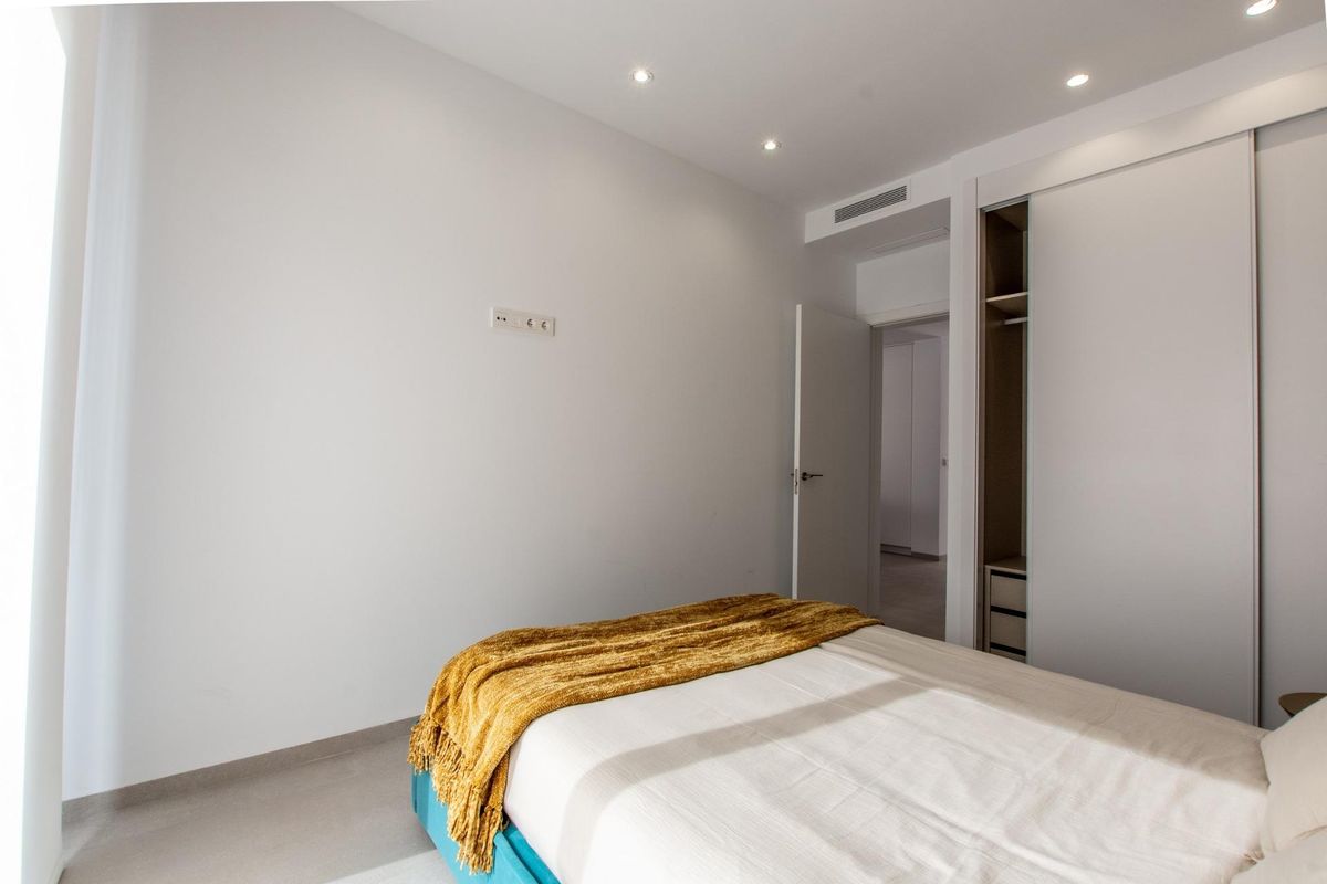 Gezellige slaapkamer met een blauwe dekbed en natuurlijk licht in een penthouse in Finestrat, Costa Blanca.