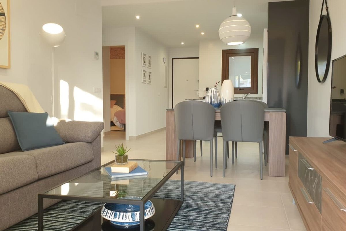 Minimalistische woonkamer met grijze bank, glazen salontafel en houten tv-meubel in Mar de Pulpi