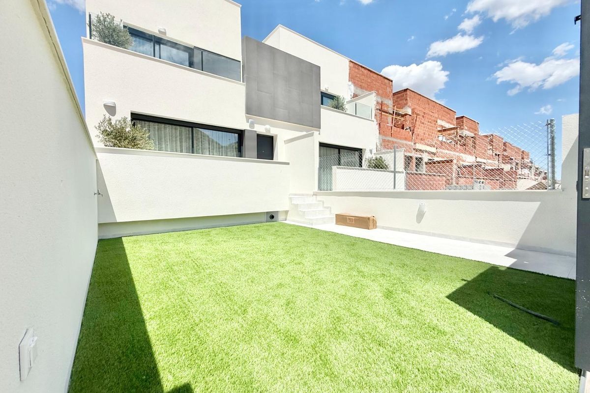 Veelzijdige achtertuin van een moderne townhouse in Cox, Costa Blanca met groen kunstgras.