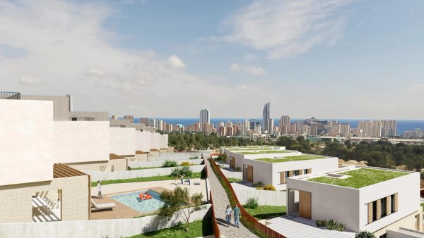 Luchtfoto van moderne villa's in Finestrat, Spanje, met stadssilhouet en zee op de achtergrond.