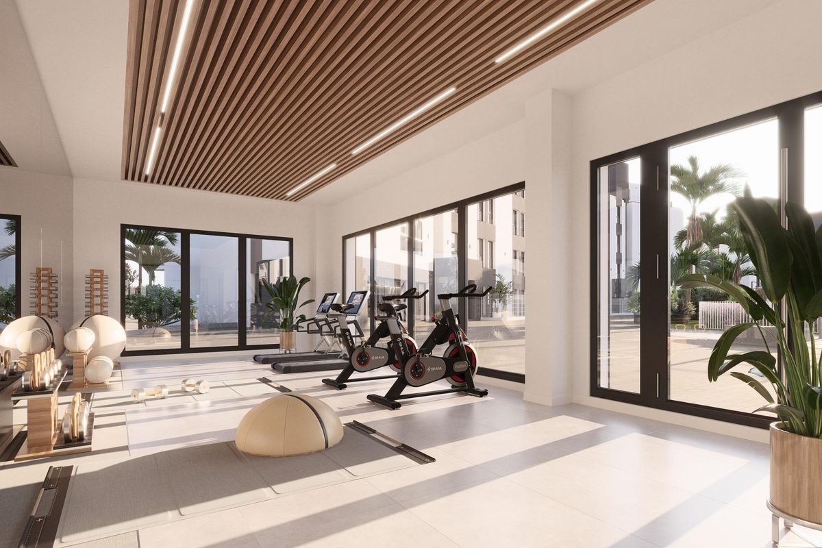 Moderne sportszaal in een 3-slaapkamer appartement in Mijas, Costa del Sol, met fitnessapparatuur en grote ramen.