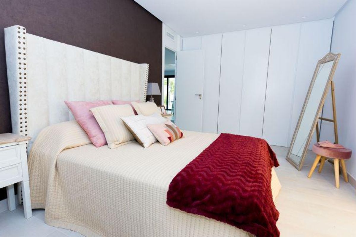 Elegante slaapkamer met wit en roze interieur en rode sprei in villa in Finestrat